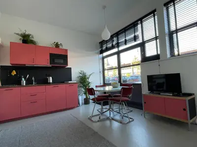 a kitchen with red cabinets and a table with chairs at Studio 28A5 with free parking place in Amsterdam