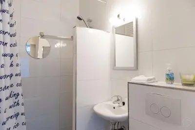 a white bathroom with a sink and a mirror at Bos en Lommer Hotel - Erasmus Park area in Amsterdam
