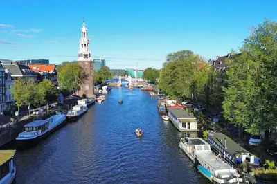 a river with boats in a city with a clock tower at Amsterdam Center - Houseboat by Captain Ricard in Amsterdam