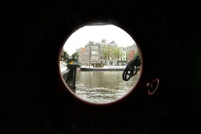 a view of a canal through a round window at Amsterdam Center - Houseboat by Captain Ricard in Amsterdam