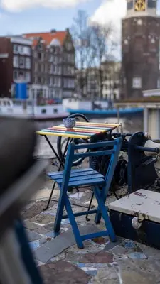 a table and a blue chair with a surfboard on it at Amsterdam Center - Houseboat by Captain Ricard in Amsterdam