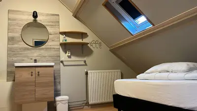 a small bedroom with a bed and a mirror at Zomerhuis Beach EnJoy in Egmond aan Zee