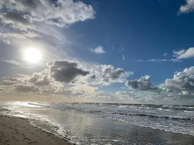 a beach with the sun reflecting on the water at Zomerhuis Beach EnJoy in Egmond aan Zee