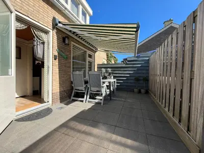 a patio with a table and chairs and stairs at Zomerhuis Beach EnJoy in Egmond aan Zee