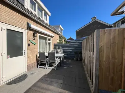 a patio with a table and chairs next to a building at Zomerhuis Beach EnJoy in Egmond aan Zee
