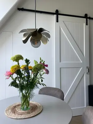 a dining room with a door and a vase of flowers at de Zuiderstolp in Zuidermeer