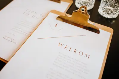 a clipboard with a wedding invitation on a table with wine glasses at Luxe stolpboerderij vol sfeer én authentieke details voor 4 in Twisk in Twisk