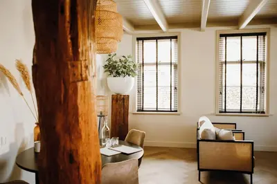 a living room with a table and chairs and windows at Luxe stolpboerderij vol sfeer én authentieke details voor 4 in Twisk in Twisk