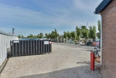 a parking lot with a gate and a building at Woonark Westeinder with kayaks close to Schiphol Airport in Aalsmeer
