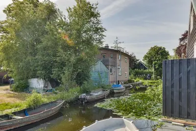 a group of boats in a river with buildings at Woonark Westeinder with kayaks close to Schiphol Airport in Aalsmeer