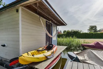 a boat sitting on a dock next to a house at Woonark Westeinder with kayaks close to Schiphol Airport in Aalsmeer