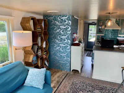 a living room with a blue couch and a kitchen at Woonark Westeinder with kayaks close to Schiphol Airport in Aalsmeer