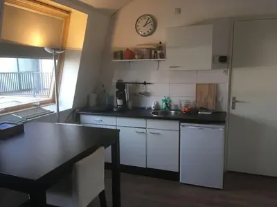 a kitchen with white cabinets and a clock on the wall at Studio, 21 minutes by bus to downtown Amsterdam in Purmerend