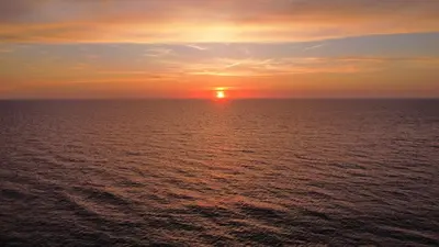 a sunset over the ocean with the sun in the sky at Ferienhaus Noordwijk Zee & Strand in Noordwijk