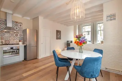 a kitchen and dining room with a white table and blue chairs at CASASdeCASPER - Apartment Alkmaar in Alkmaar