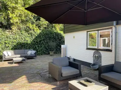 a patio with two couches and an umbrella at Bergense Duyn by Droomvilla in Bergen