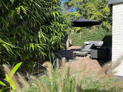 a patio with some chairs and an umbrella at Bergense Duyn by Droomvilla in Bergen