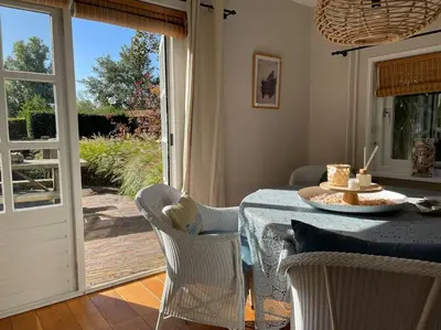 a dining room with a table and chairs and a sliding glass door at Bergense Duyn by Droomvilla in Bergen