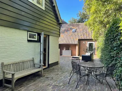 a patio with a table and a bench next to a building at Bergense Duyn by Droomvilla in Bergen