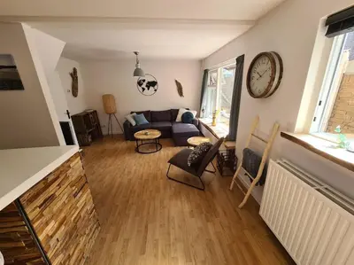 a living room with a couch and a clock on the wall at Have a nice stay! - North Sea Home in Noordwijk aan Zee