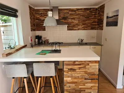 a kitchen with a counter with stools in it at Have a nice stay! - North Sea Home in Noordwijk aan Zee