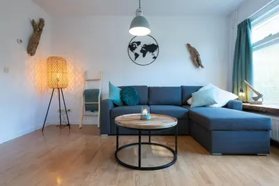 a living room with a blue couch and a table at Have a nice stay! - North Sea Home in Noordwijk aan Zee