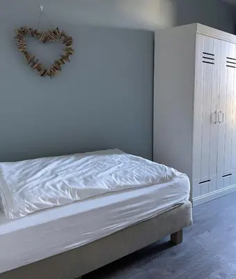 a bedroom with a bed with a heart sign on the wall at Boulevard Suites in Egmond aan Zee