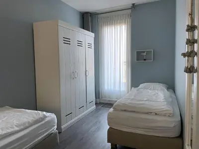 a bedroom with two beds and a white cabinet at Boulevard Suites in Egmond aan Zee