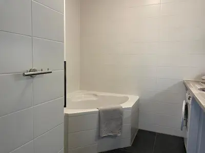a white bathroom with a tub and a sink at Boulevard Suites in Egmond aan Zee