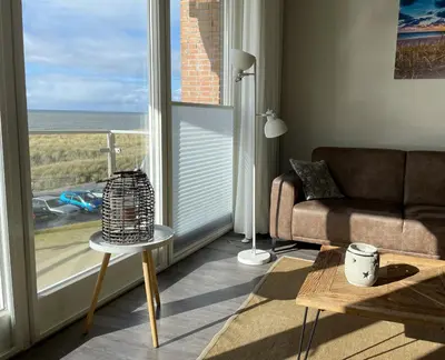 a living room with a couch and a large window at Boulevard Suites in Egmond aan Zee