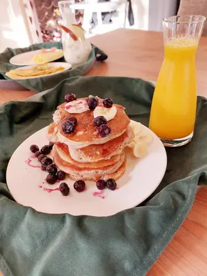 a plate of pancakes with berries and a glass of orange juice at BNBSpanbroek in Spanbroek