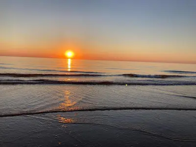 a sunset on a beach with the ocean at Kustappartementenkatwijk 2F in Katwijk aan Zee