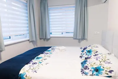 a bedroom with a bed with a floral comforter and a window at Kustappartementenkatwijk 2F in Katwijk aan Zee
