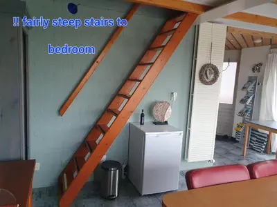 a wooden staircase in a room with a refrigerator at Walvisch van Ghyspe in Wormer