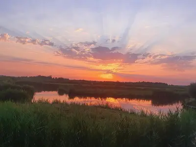 a sunset over a body of water with the sun setting at Walvisch van Ghyspe in Wormer