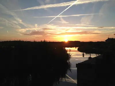 a sunset over a river with the sun in the sky at Walvisch van Ghyspe in Wormer