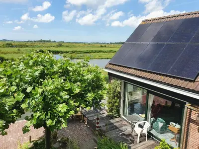 a house with solar panels on the roof and a tree at Walvisch van Ghyspe in Wormer