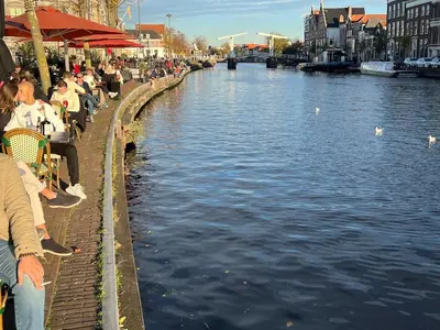 a group of people sitting at tables next to a river at GuesthouseOne in Haarlem