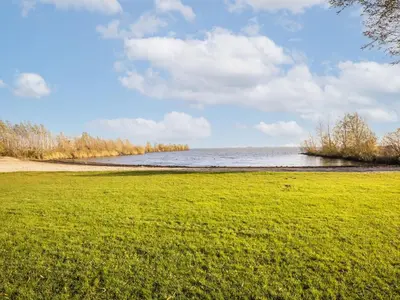a field of grass next to a body of water at Beautiful houseboat with shared pool in Volendam