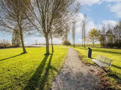 a park with a bench and trees in a field at Beautiful houseboat with shared pool in Volendam