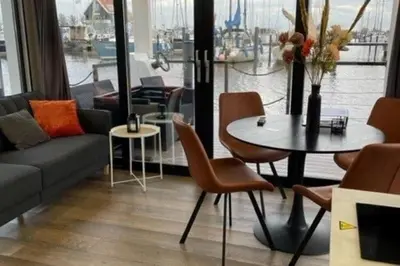 a living room with a couch and a table with chairs at Beautiful houseboat with shared pool in Volendam
