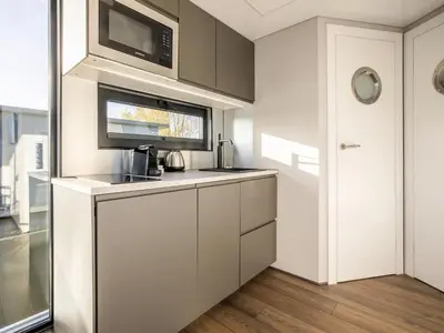 a kitchen with white cabinets and a microwave at Beautiful houseboat with shared pool in Volendam