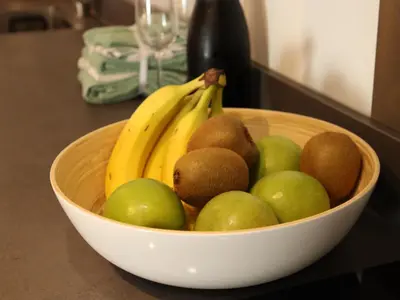 a bowl of fruit on a counter with bananas and kiwis at Coolest Apartments in Haarlem City - close to Beach and Amsterdam in Haarlem
