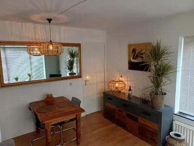 a living room with a table and a dresser at 't Zwanennest Egmond aan Zee in Egmond aan Zee