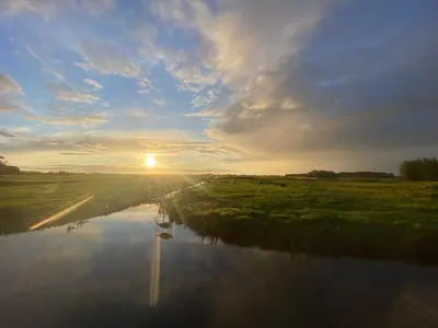 a sunrise over a river with the sun in the sky at Natuurhuisje Gouderak in Gouderak