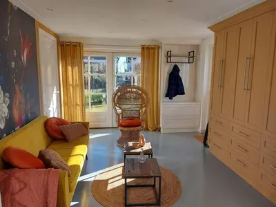 a living room with a yellow couch and a chair at Tiny house Wakker in Eemnes