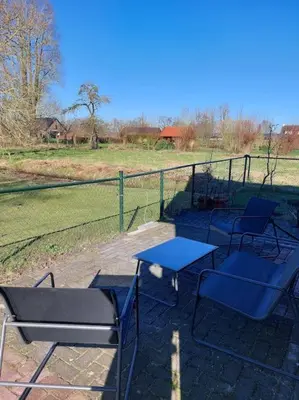 a patio with blue tables and chairs and a fence at Tiny house Wakker in Eemnes