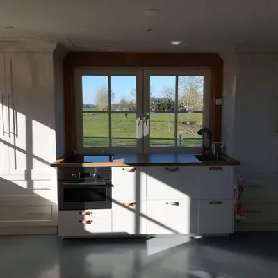 a kitchen with a stove and a window with a field at Tiny house Wakker in Eemnes