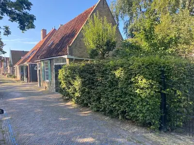 a building with a hedge next to a street at Characteristic two bedroom home in Edam