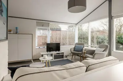 a living room with a couch and chairs and a tv at Rekerlanden 90 in Schoorldam
